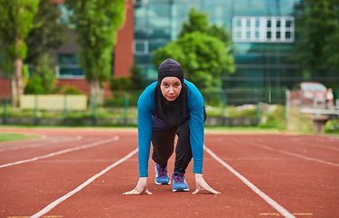 Image showing Muslim woman in burqa in sporty Muslim clothes in starting pose for running