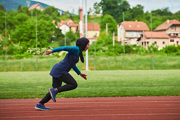 Image showing A muslim woman in a burqa sports muslim clothes running on a marathon course and preparing for upcoming competitions