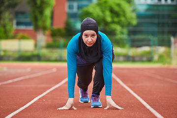 Image showing Muslim woman in burqa in sporty Muslim clothes in starting pose for running