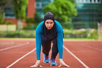 Image showing Muslim woman in burqa in sporty Muslim clothes in starting pose for running