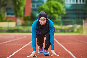 Image showing Muslim woman in burqa in sporty Muslim clothes in starting pose for running