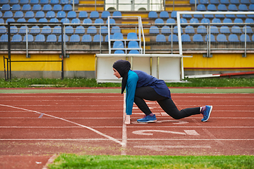 Image showing Muslim woman in burqa in sporty Muslim clothes in starting pose for running