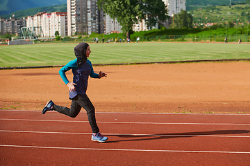 Image showing A muslim woman in a burqa sports muslim clothes running on a marathon course and preparing for upcoming competitions