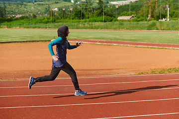 Image showing A muslim woman in a burqa sports muslim clothes running on a marathon course and preparing for upcoming competitions