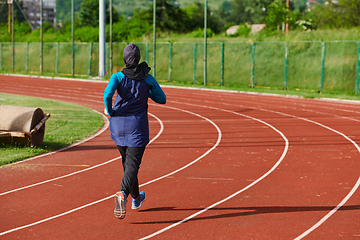 Image showing A muslim woman in a burqa sports muslim clothes running on a marathon course and preparing for upcoming competitions