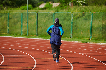 Image showing A muslim woman in a burqa sports muslim clothes running on a marathon course and preparing for upcoming competitions