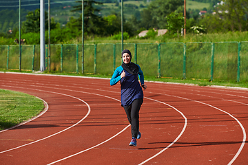 Image showing A muslim woman in a burqa sports muslim clothes running on a marathon course and preparing for upcoming competitions