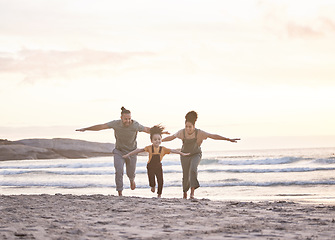 Image showing Happy, freedom and a family at the beach during sunset for flying, playing and bonding at the ocean. Smile, carefree and an interracial child, mother and father at the sea for a vacation or summer