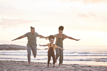 Image showing Travel, freedom and a family at the beach during sunset for flying, playing and bonding at the ocean. Smile, holiday and an interracial child, mother and father at the sea for a vacation or summer