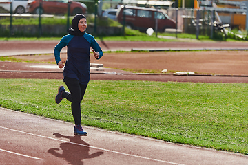 Image showing A muslim woman in a burqa sports muslim clothes running on a marathon course and preparing for upcoming competitions