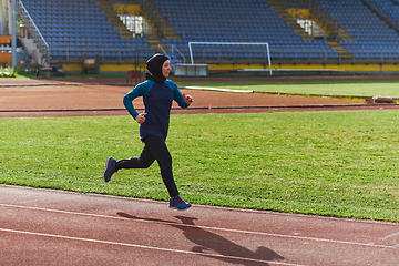 Image showing A muslim woman in a burqa sports muslim clothes running on a marathon course and preparing for upcoming competitions