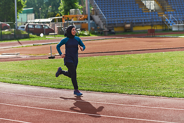 Image showing A muslim woman in a burqa sports muslim clothes running on a marathon course and preparing for upcoming competitions