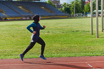 Image showing A muslim woman in a burqa sports muslim clothes running on a marathon course and preparing for upcoming competitions