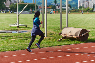 Image showing A muslim woman in a burqa sports muslim clothes running on a marathon course and preparing for upcoming competitions