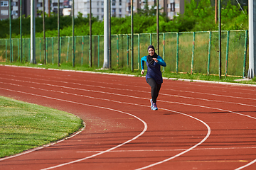 Image showing A muslim woman in a burqa sports muslim clothes running on a marathon course and preparing for upcoming competitions