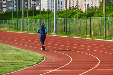 Image showing A muslim woman in a burqa sports muslim clothes running on a marathon course and preparing for upcoming competitions