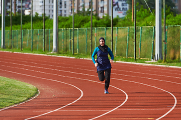 Image showing A muslim woman in a burqa sports muslim clothes running on a marathon course and preparing for upcoming competitions