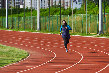 Image showing A muslim woman in a burqa sports muslim clothes running on a marathon course and preparing for upcoming competitions