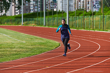 Image showing A muslim woman in a burqa sports muslim clothes running on a marathon course and preparing for upcoming competitions