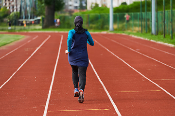 Image showing A muslim woman in a burqa sports muslim clothes running on a marathon course and preparing for upcoming competitions