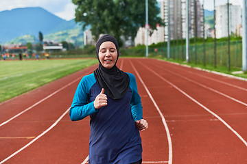 Image showing A muslim woman in a burqa sports muslim clothes running on a marathon course and preparing for upcoming competitions