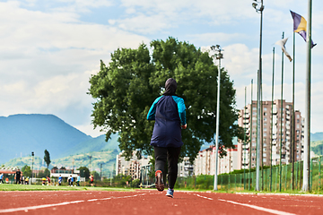 Image showing A muslim woman in a burqa sports muslim clothes running on a marathon course and preparing for upcoming competitions