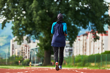 Image showing A muslim woman in a burqa sports muslim clothes running on a marathon course and preparing for upcoming competitions