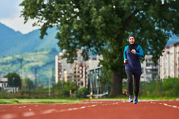 Image showing A muslim woman in a burqa sports muslim clothes running on a marathon course and preparing for upcoming competitions