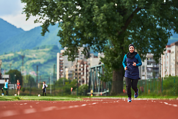 Image showing A muslim woman in a burqa sports muslim clothes running on a marathon course and preparing for upcoming competitions