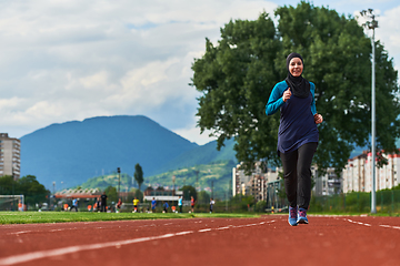 Image showing A muslim woman in a burqa sports muslim clothes running on a marathon course and preparing for upcoming competitions