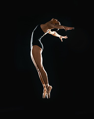 Image showing Art, ballet jumping and woman on black background in dance performance with balance, action and talent. Dark aesthetic, flexible ballerina or dancer training with fitness, creativity and studio show.