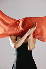 Image showing Fashion, textile and wind with a model in studio on a gray background for runway or magazine cover style. Abstract, fabric and hidden face with a trendy young woman posing in a material outfit