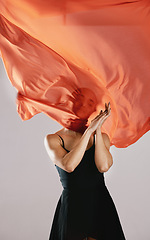 Image showing Fashion, fabric and breeze with a model in studio on a gray background for runway or magazine cover style. Abstract, textile wind and hidden face with a trendy young woman posing in a material outfit