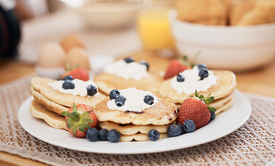 Image showing Pancakes, breakfast and fruits on table in home in the morning for protein. Bread waffle, cream and food for eating, healthy diet and strawberry in wellness nutrition, blueberry and egg meal on plate