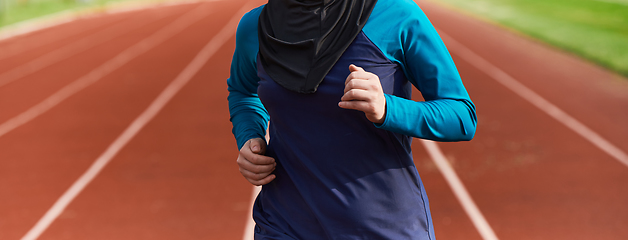 Image showing A muslim woman in a burqa sports muslim clothes running on a marathon course and preparing for upcoming competitions