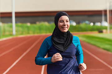 Image showing A muslim woman in a burqa sports muslim clothes running on a marathon course and preparing for upcoming competitions