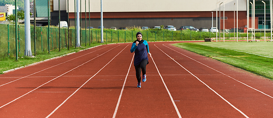 Image showing A muslim woman in a burqa sports muslim clothes running on a marathon course and preparing for upcoming competitions