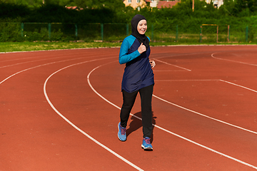 Image showing A muslim woman in a burqa sports muslim clothes running on a marathon course and preparing for upcoming competitions