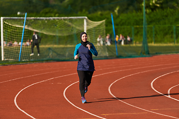 Image showing A muslim woman in a burqa sports muslim clothes running on a marathon course and preparing for upcoming competitions