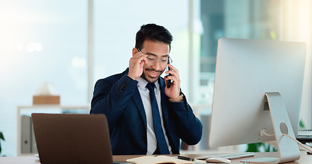 Image showing Happy business man talking on his phone while working on a computer and smiling alone at work. Young corporate professional having a discussion and explaining project details to a colleague or client