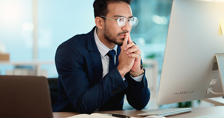 Image showing Thinking IT manager working on a desktop computer and laptop in a modern office. Information Technology software engineer analyzing data management system. Thoughtful analyst looking for a solution