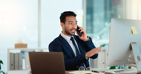 Image showing Happy business man talking on his phone while working on a computer and smiling alone at work. Young corporate professional having a discussion and explaining project details to a colleague or client