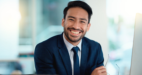 Image showing Happy young business man looking ready for the day while working on a computer and smiling alone at work. Portrait of one corporate professional looking confident and successful in the office