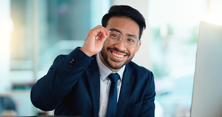 Image showing Happy young business man looking ready for the day while working on a computer and smiling alone at work. Portrait of one corporate professional looking confident and successful in the office