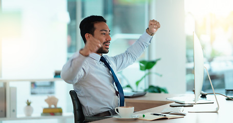 Image showing Excited business man cheering at his desk. Successful male banker or happy financial advisor celebrating his trading victory in a modern office. Young guy reading good news on his computer at work.