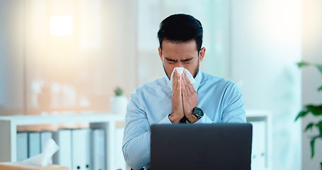 Image showing A modern business man feeling sick with covid fatigue while working online at a desk on his laptop. Closeup of an male corporate manager blowing his nose. An ill office worker frustrated at work.