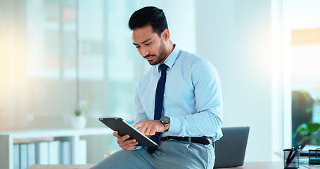 Image showing Successful young business man laughing while browsing on a tablet in the office. Portrait of a confident male corporate professional feeling positive after completing a deal or finishing a task