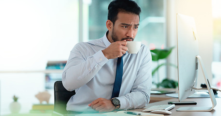 Image showing Exhausted businessman typing on a computer working and sipping coffee in a corporate office. A male employee sitting at a desk feeling sleepy and yawning tired from overworked job and drinking coffee