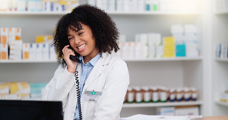 Image showing Friendly pharmacist talking on the telephone and checking something on her computer in a pharmacy. Woman using pc to access drug database for inventory check or access customers prescription online