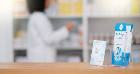 Image showing Focus on an information pamphlet on a counter at a pharmacy, advertising treatment and health care with a pharmacist packing rows medication on a shelf in a modern drugstore against blur background